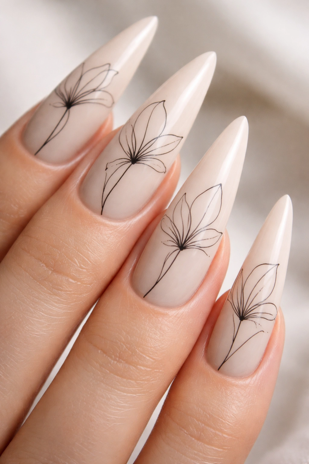 Pale neutral stiletto nails with minimalist lily line artwork