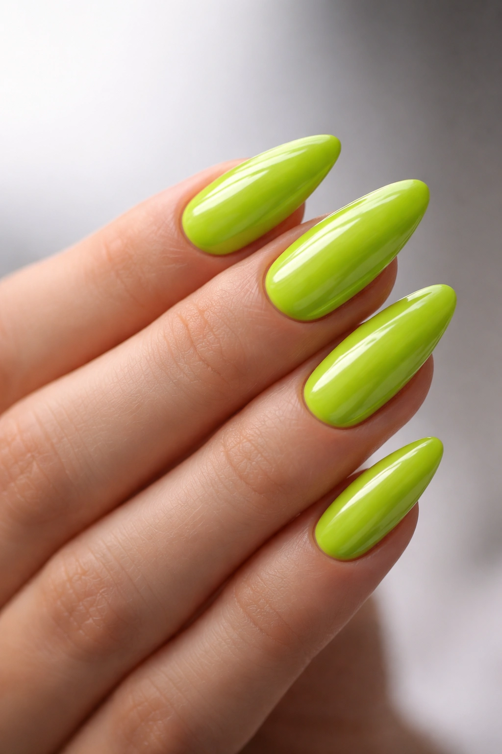 Close-up of lime green almond nails with high-gloss finish on a bare hand