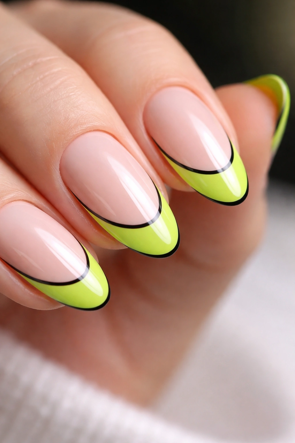 Close-up of a short almond nail with lime tip and black outline along the smile line