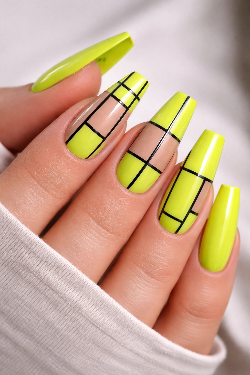 Close-up of lime neon ballerina nails with a black grid grid lines on a glossy short tip