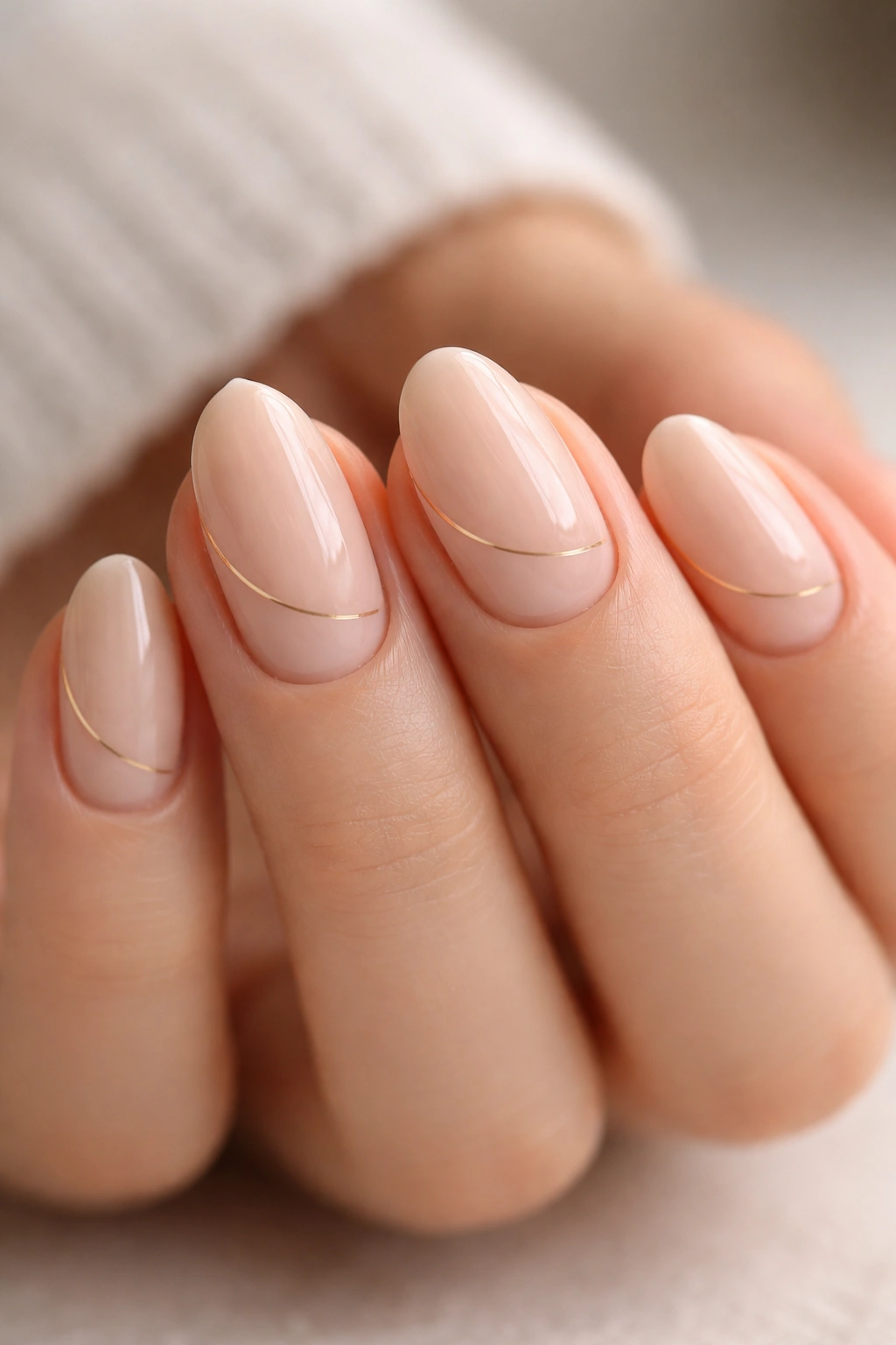 Close-up of short almond nails with a single thin line near the cuticle on nude base