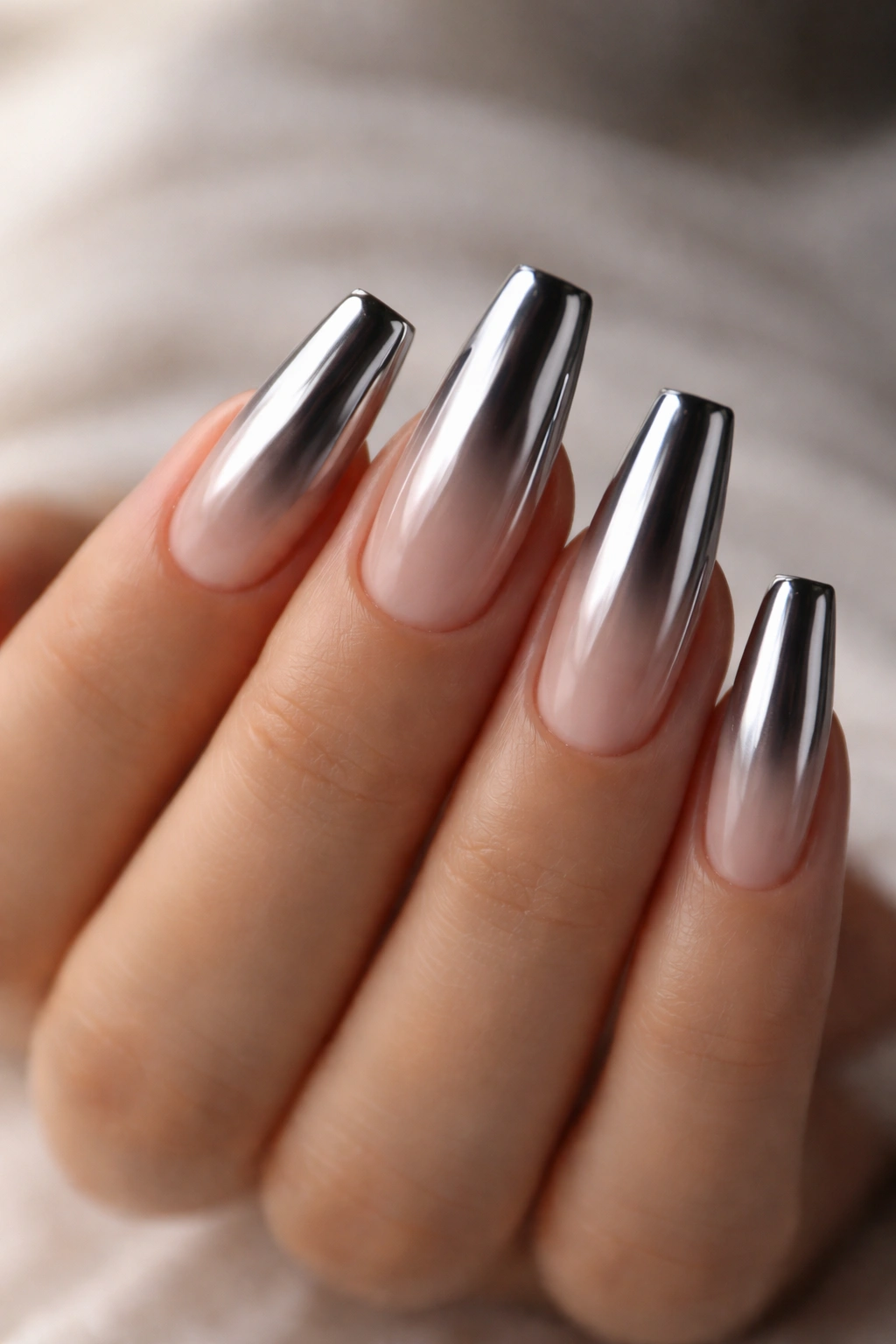 Close-up of medium coffin nails with liquid chrome gradient on a nude base