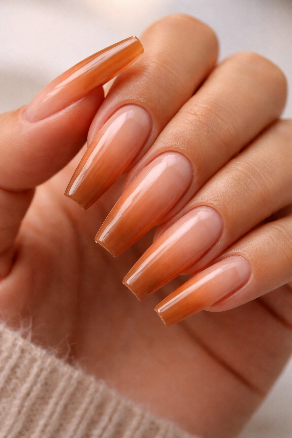 Close-up of long warm-toned coffin nails showing base growth and tip wear