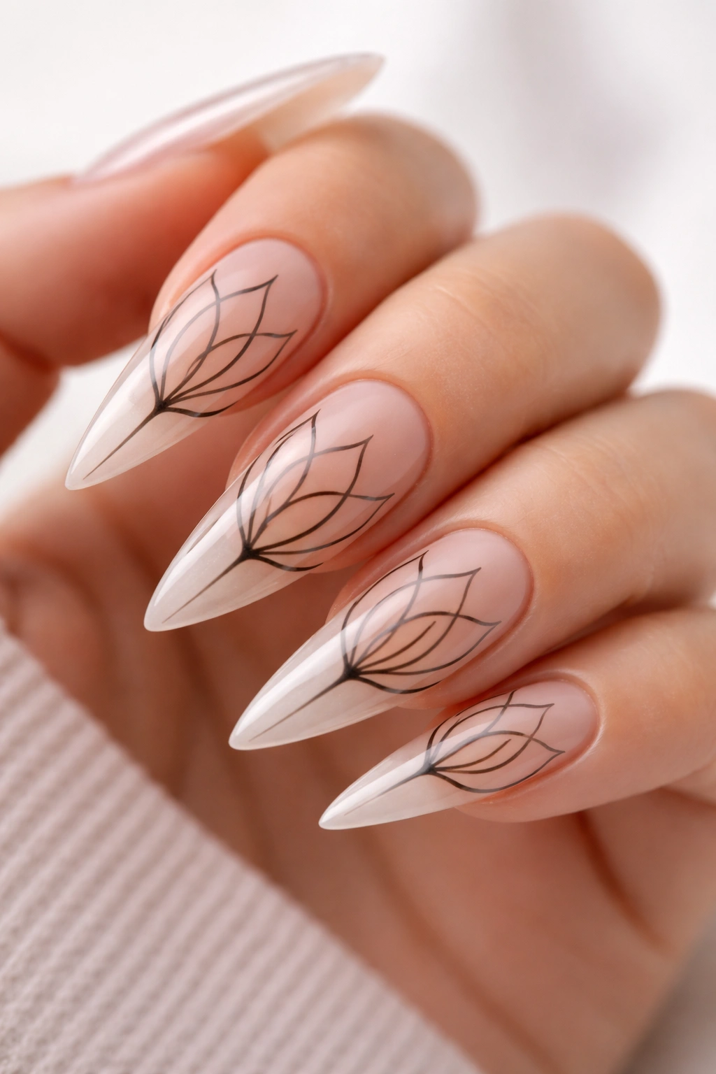 Stiletto nails featuring a lotus outline with negative space on a neutral base.