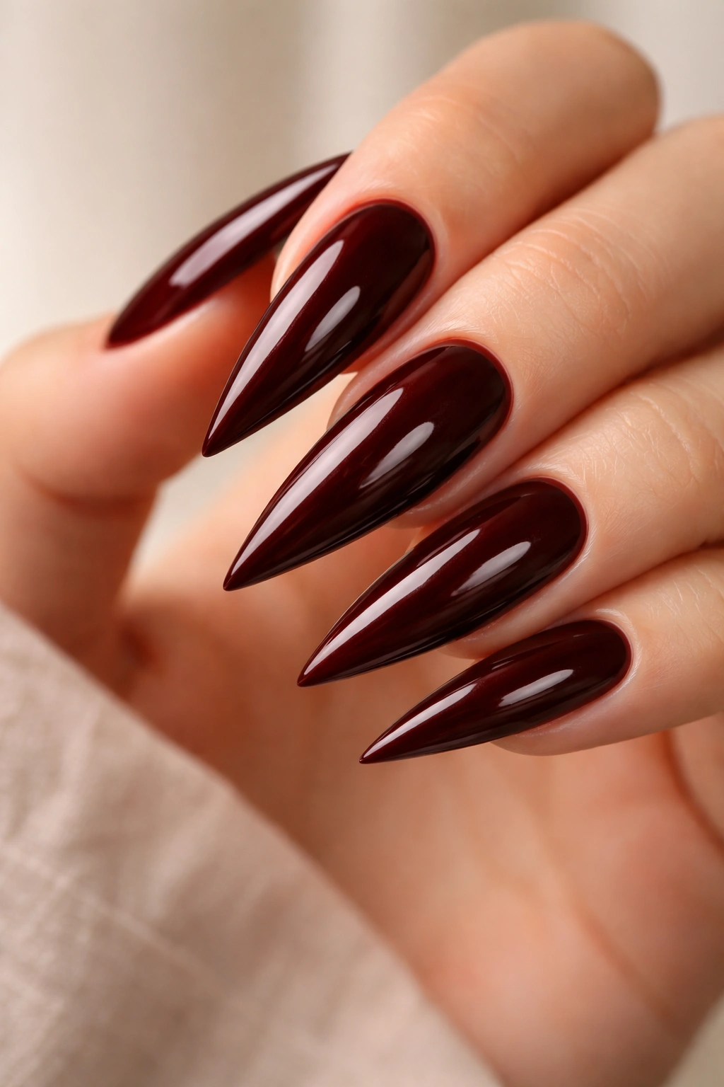 Close-up of deep mahogany brown stiletto nails with red undertones