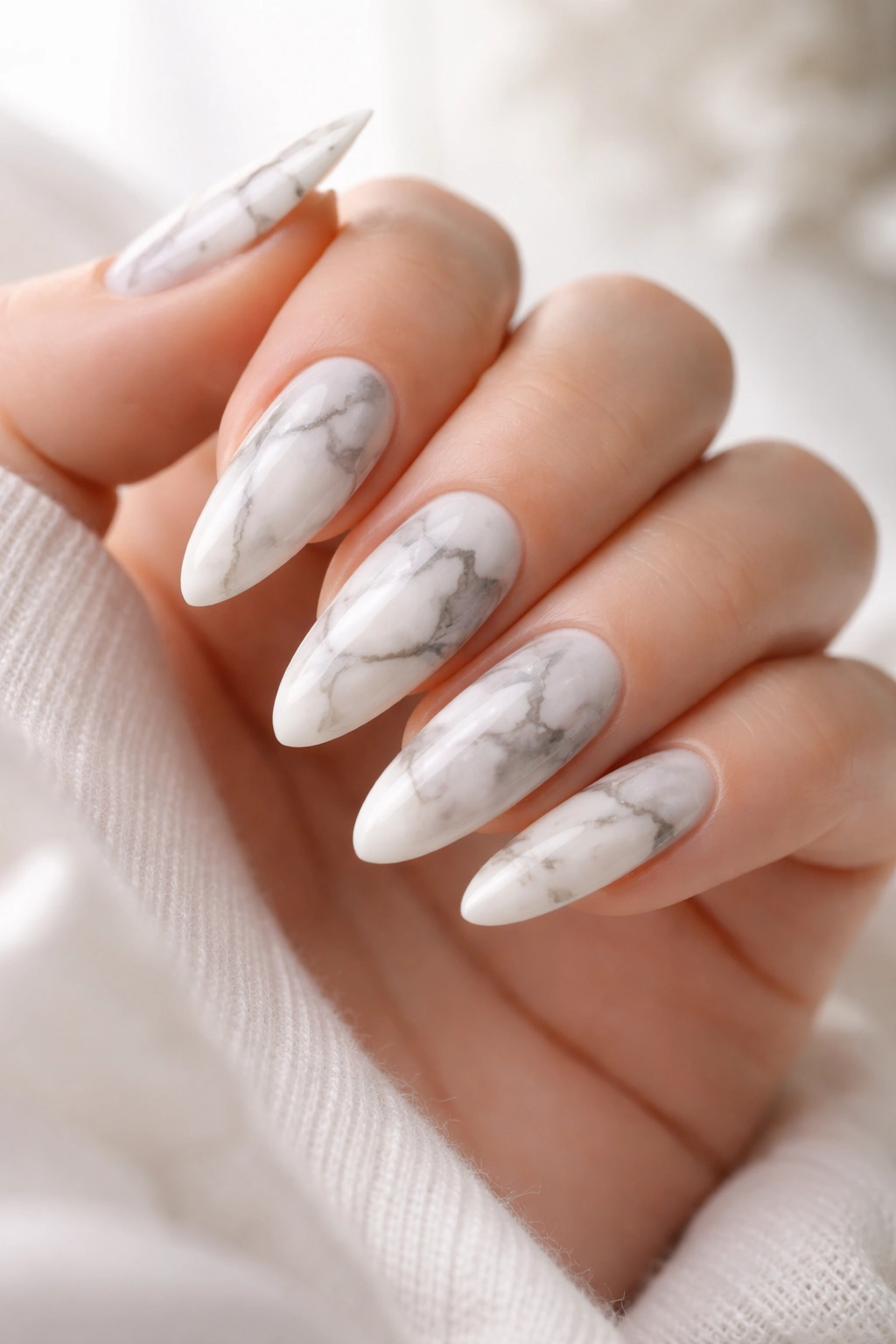 Close-up of marble almond nails with white and gray veining