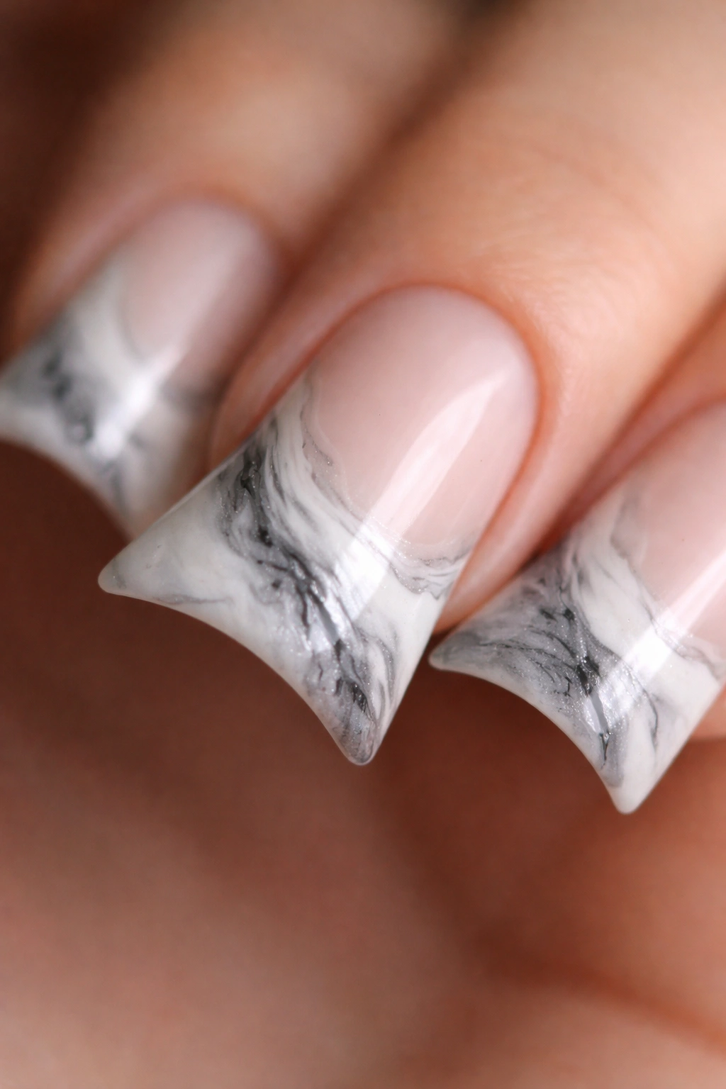 Close-up of a duck nail with white and gray marble pattern following the curved tip.