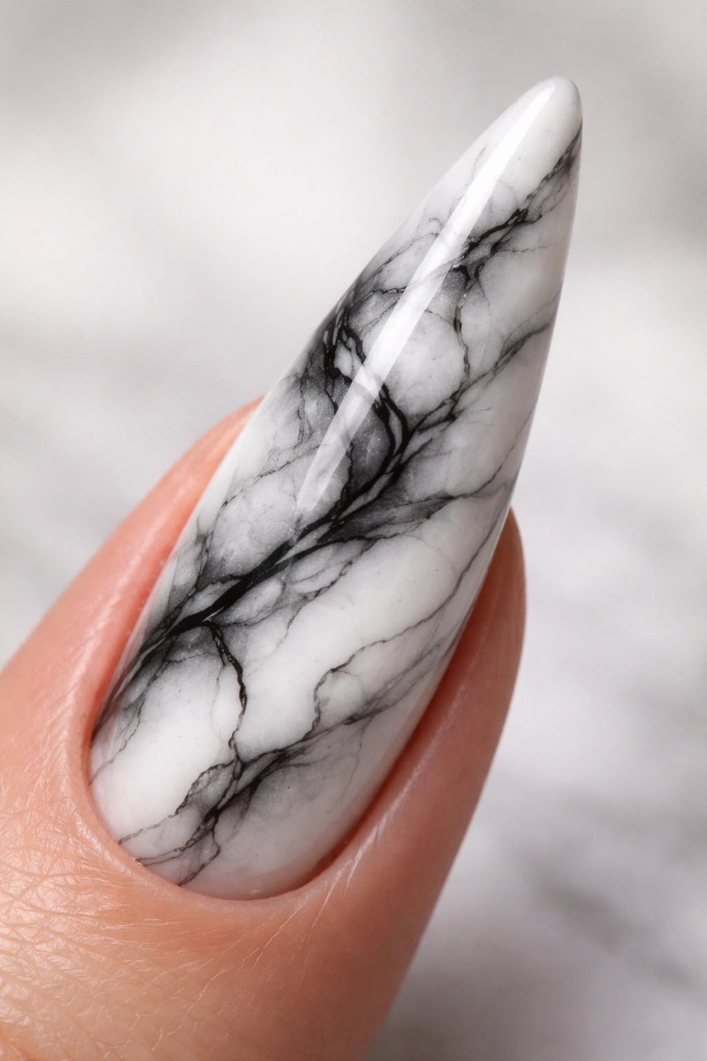Stiletto nail with black, white, and gray marble pattern and glossy finish