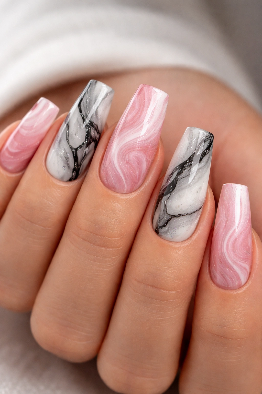 Close-up of marble-style acrylic nails with pink-white swirls and black veining