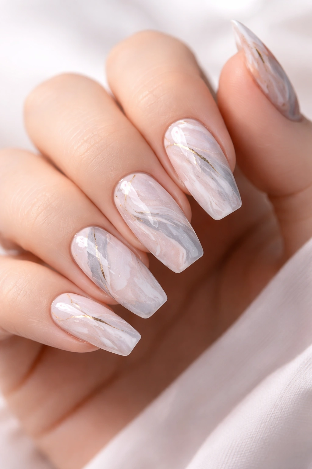 Close-up of marble nails with gray white swirls and pastel pink accents