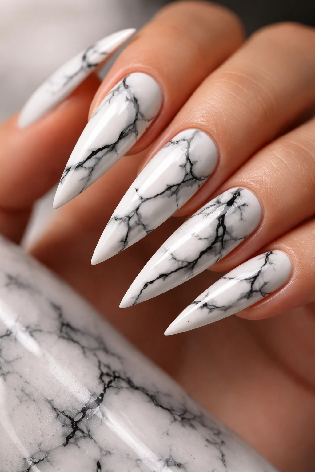 Close-up of stiletto nails with white marble texture and black veins