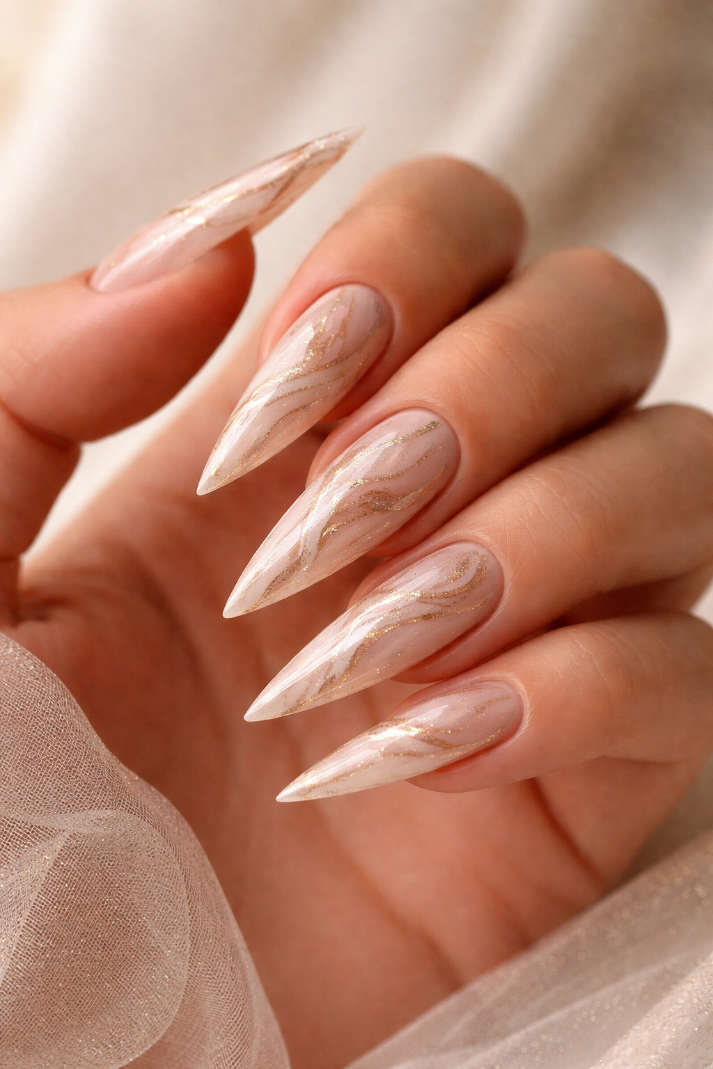 Nude nails with champagne marble swirls in a studio setting