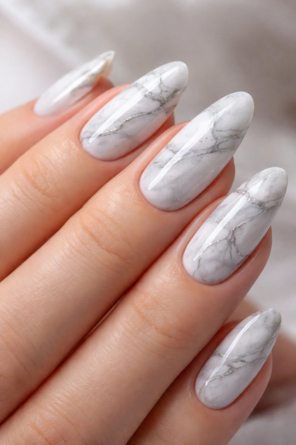 Close-up of marble dip powder nails with white and gray veining on a hand