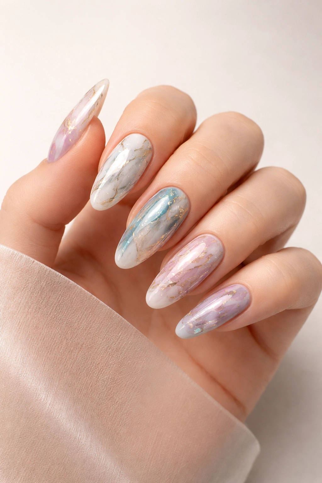 Close-up of a hand with long round marble nails in various marble patterns on a plain background.