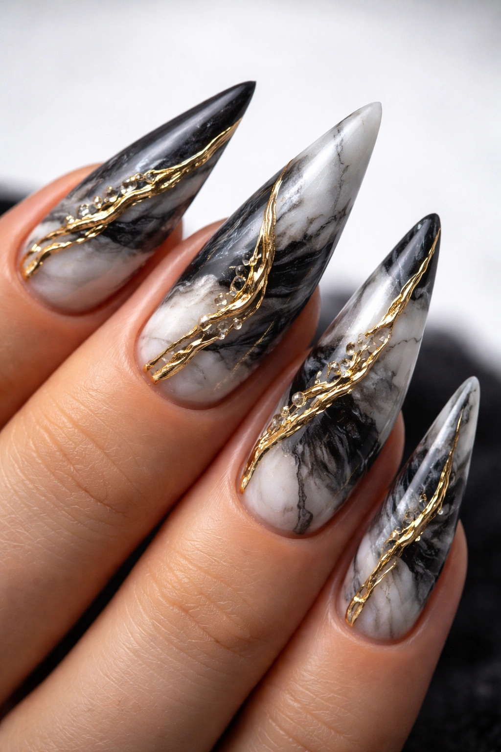 Close-up of black and white marble-styled nails with a raised gold vein accent