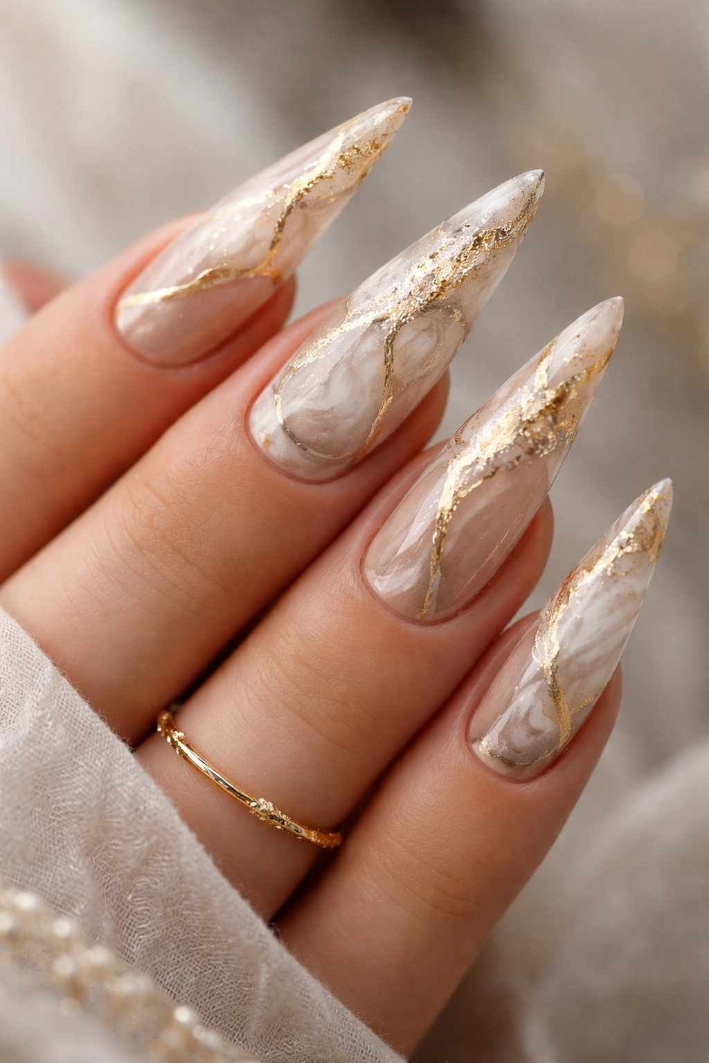 Close-up of gold-veined marble nails on stiletto shape
