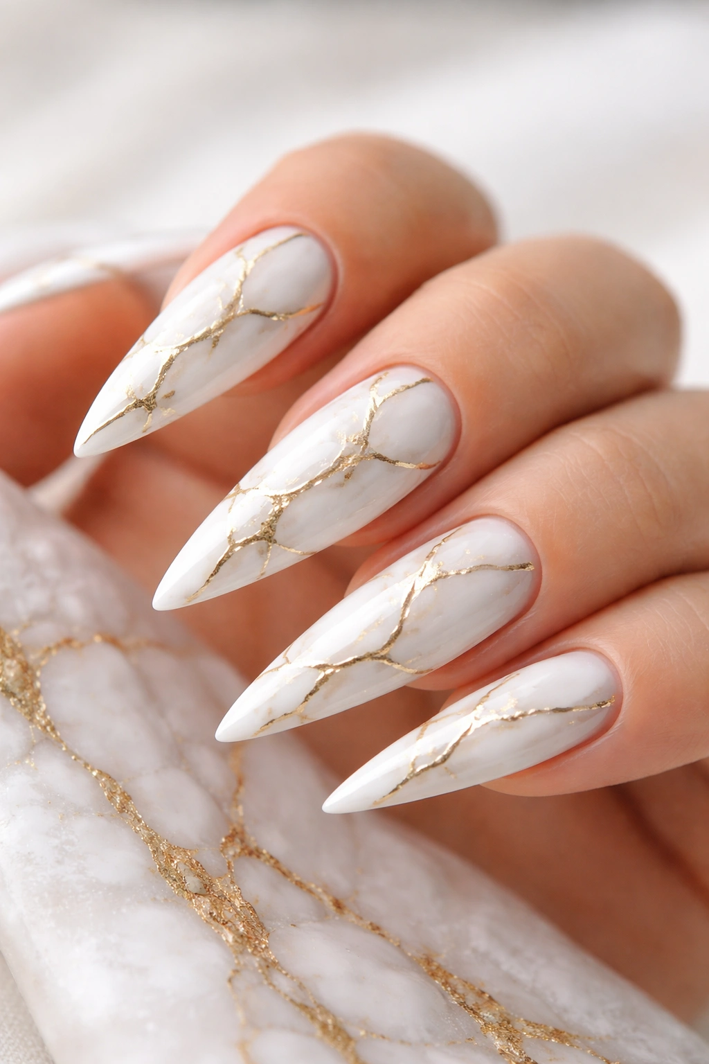 White stiletto nails with gold marble veining