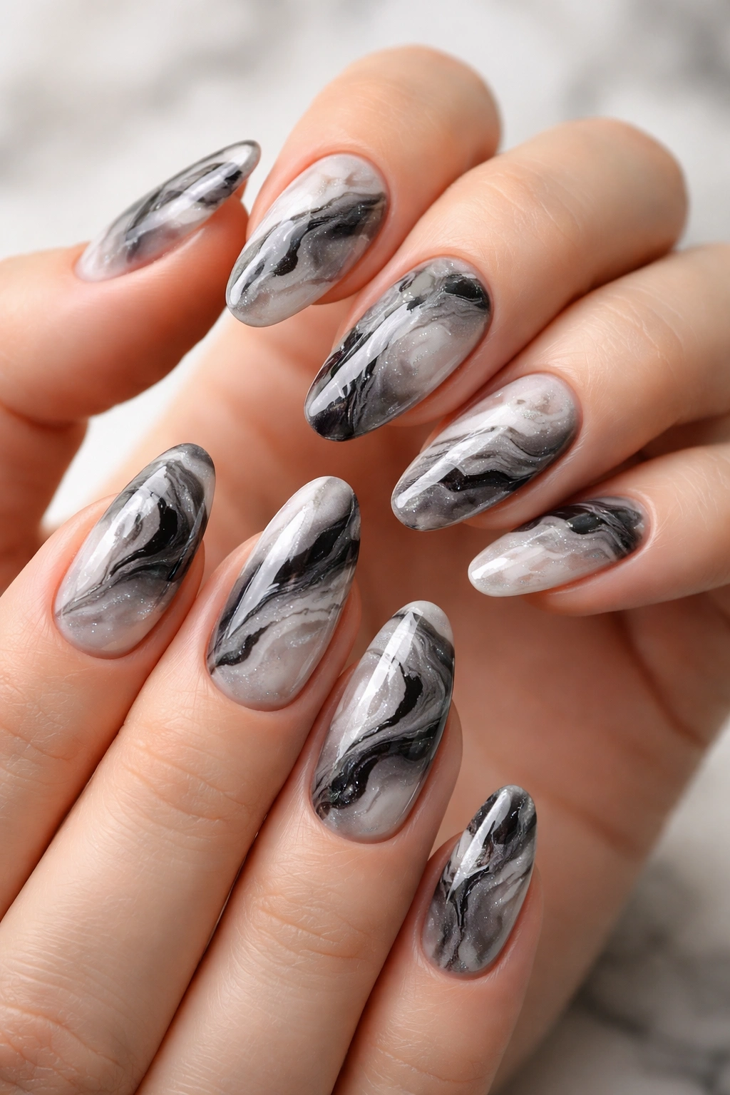 Close-up of marble nails on fingertips with black white and gray swirls