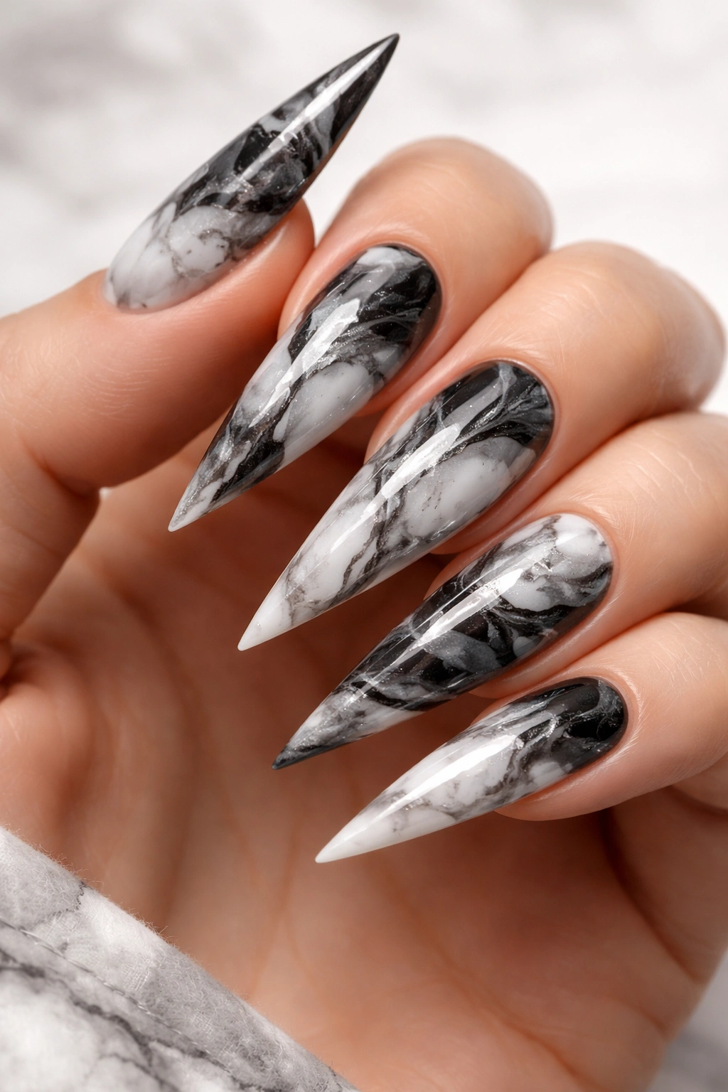 Close-up of marble luxury stilettos nails with black white gray veining