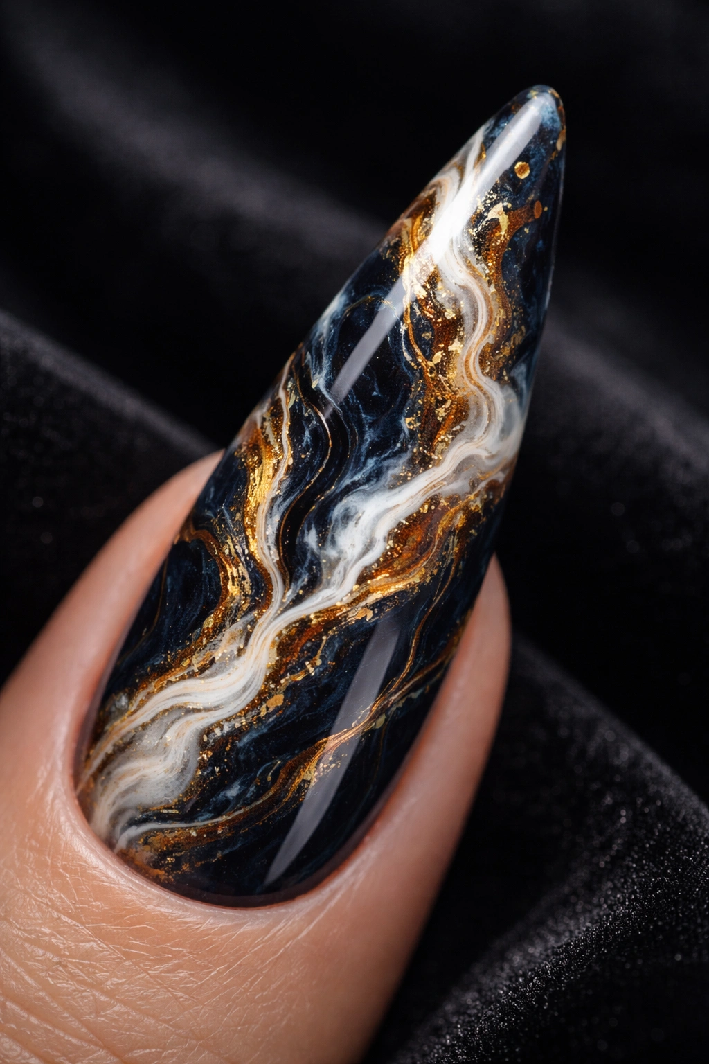Close-up of a stiletto nail with chaotic marble veining on a dark base