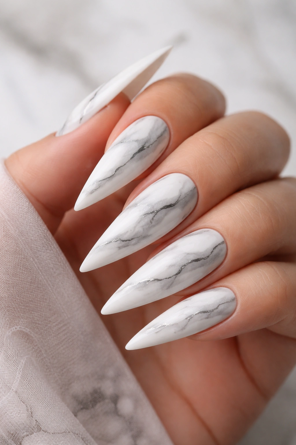 White stiletto nails with gray marble swirls and a vein line