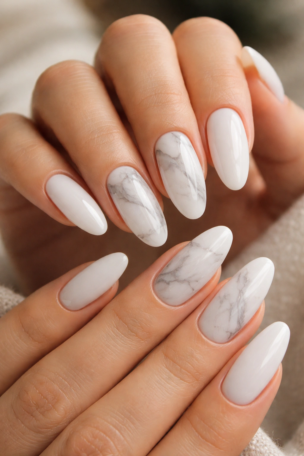 Close-up of long oval acrylic nails with light marble veining