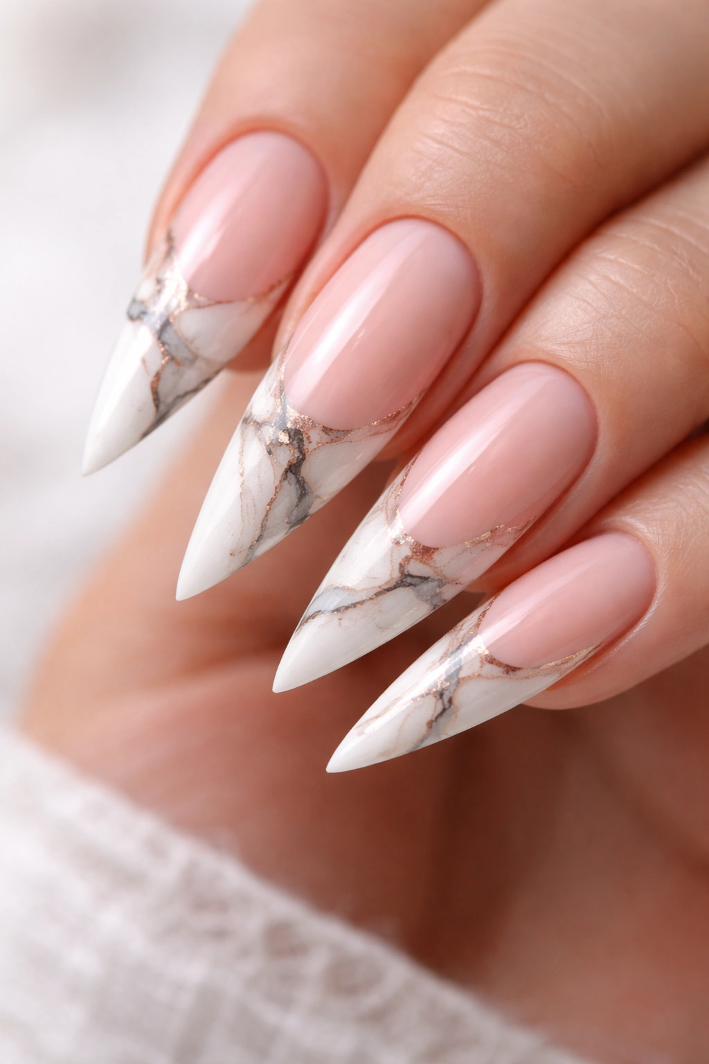 Close-up of stiletto nails with marble swirl on the white tip and pale pink base