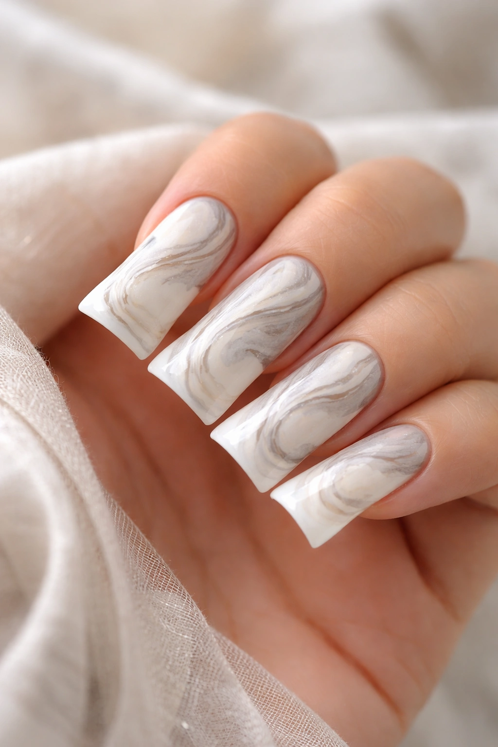Close-up of marble-patterned white duck nails on a hand