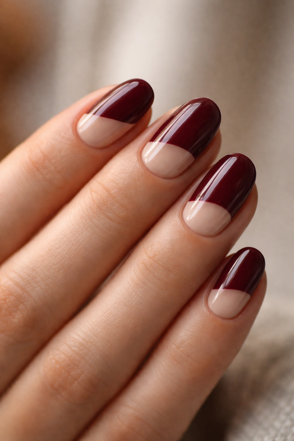 Close-up of maroon nails with negative space on short oval nails