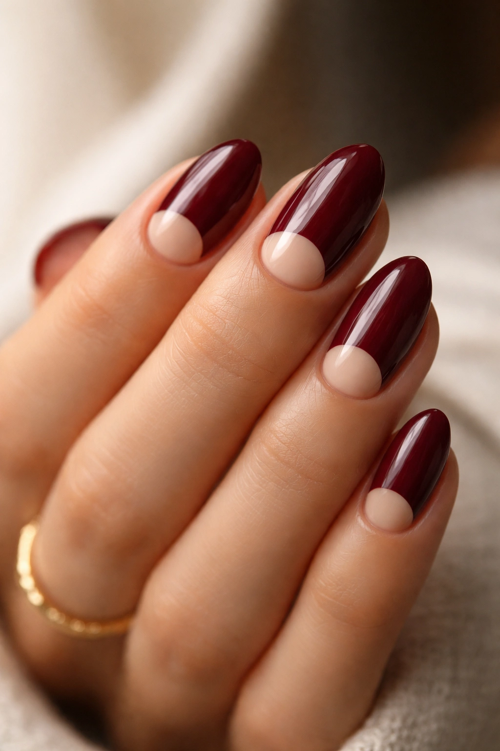 Short almond nails with maroon polish and nude half-moon near base