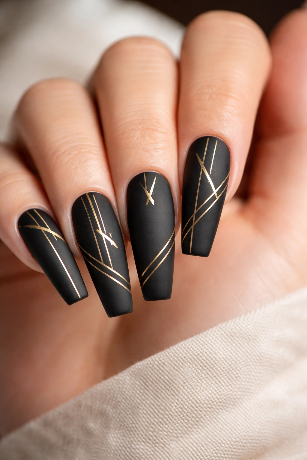 Close-up of matte black coffin nails with gold geometric accents