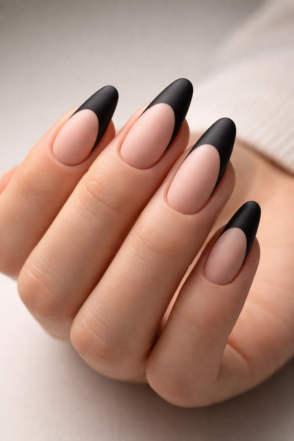 Close-up of hand with matte black tips on nude base