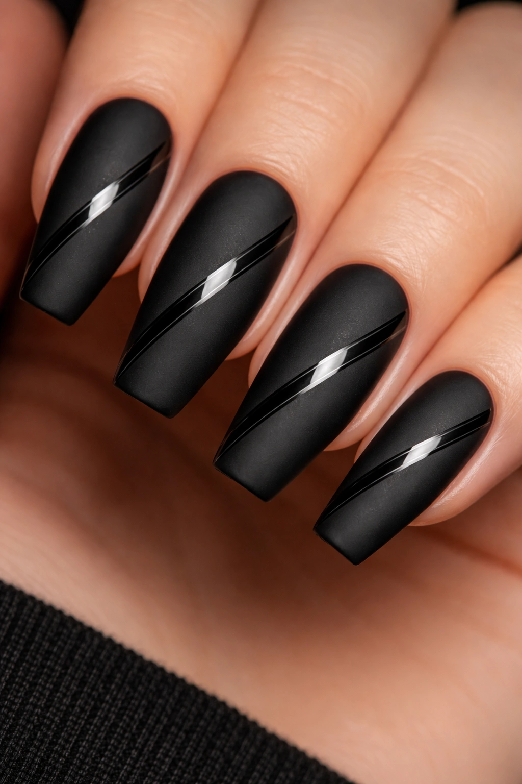 Close-up of matte black ballerina nails featuring a diagonal glossy band