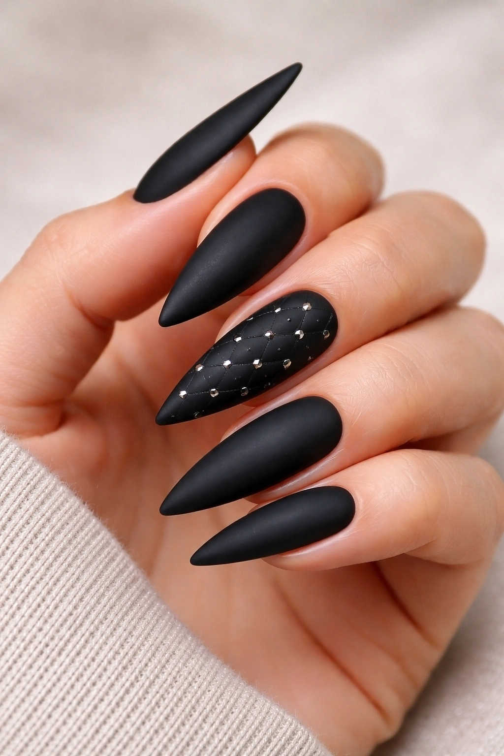 Close-up of matte black nails with diamond-pattern studs