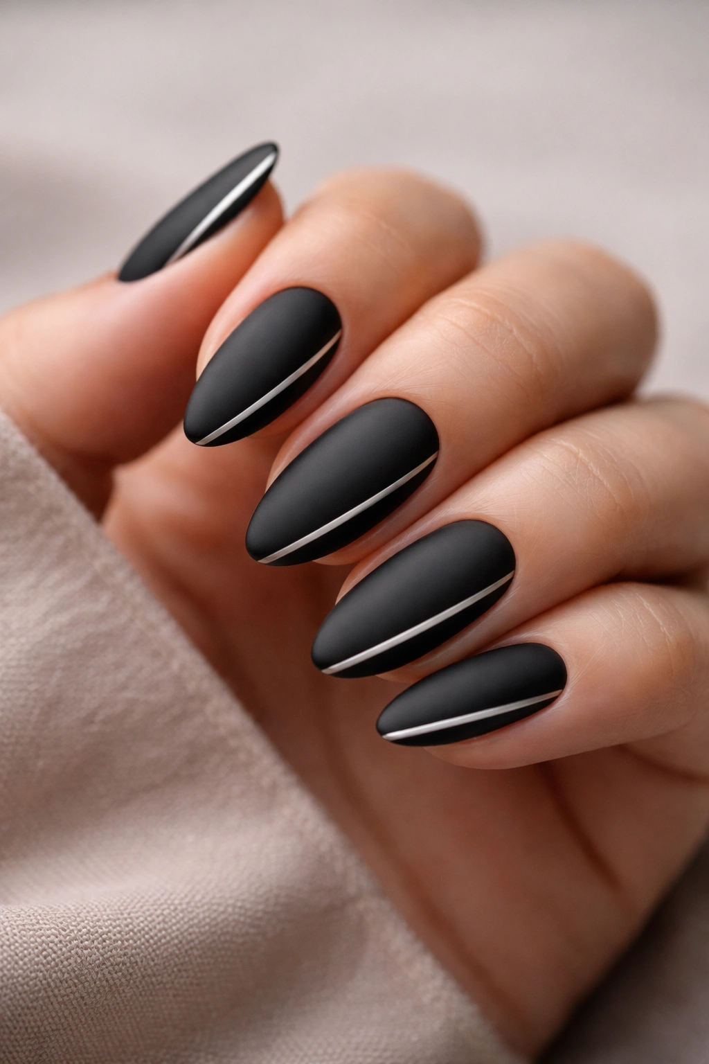 Almond nails matte black with thin silver stripes.