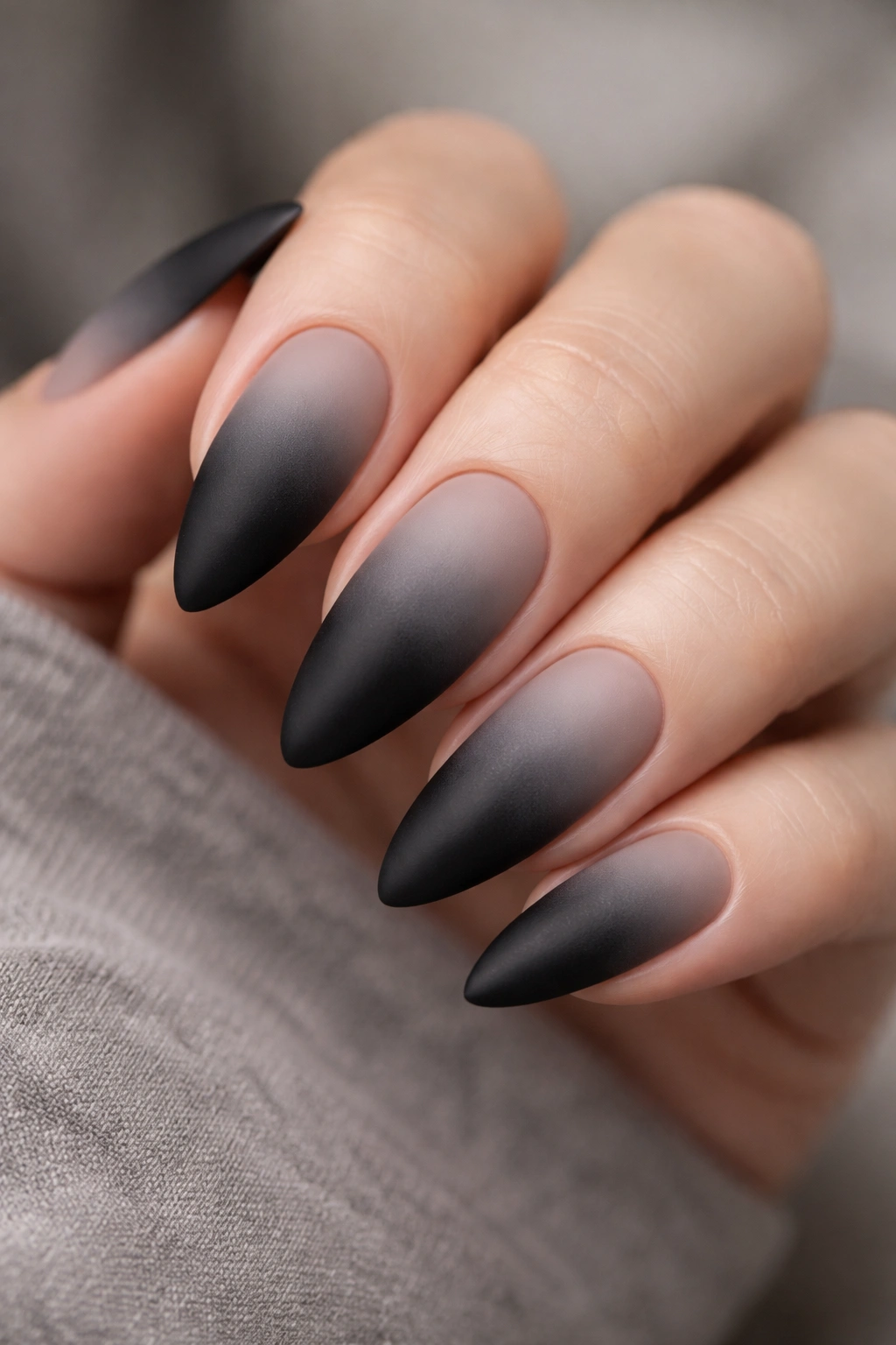 Close-up of matte black ombre nails on almond nails