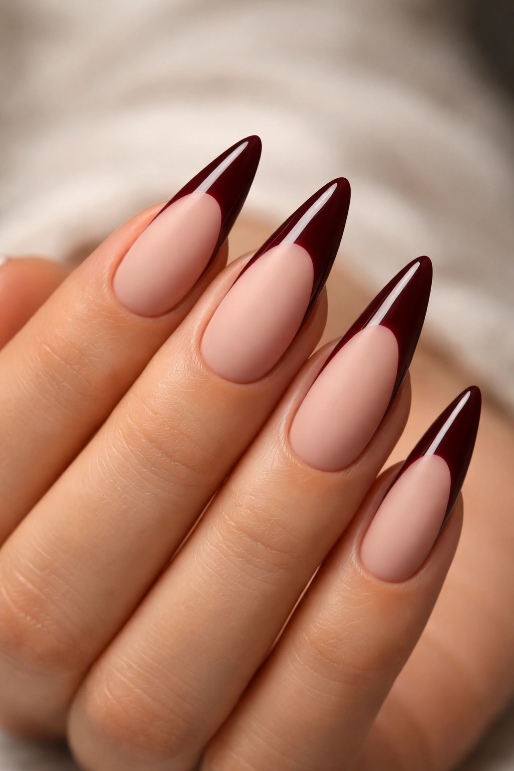 Close-up of burgundy tips with glossy edge on matte nude nails