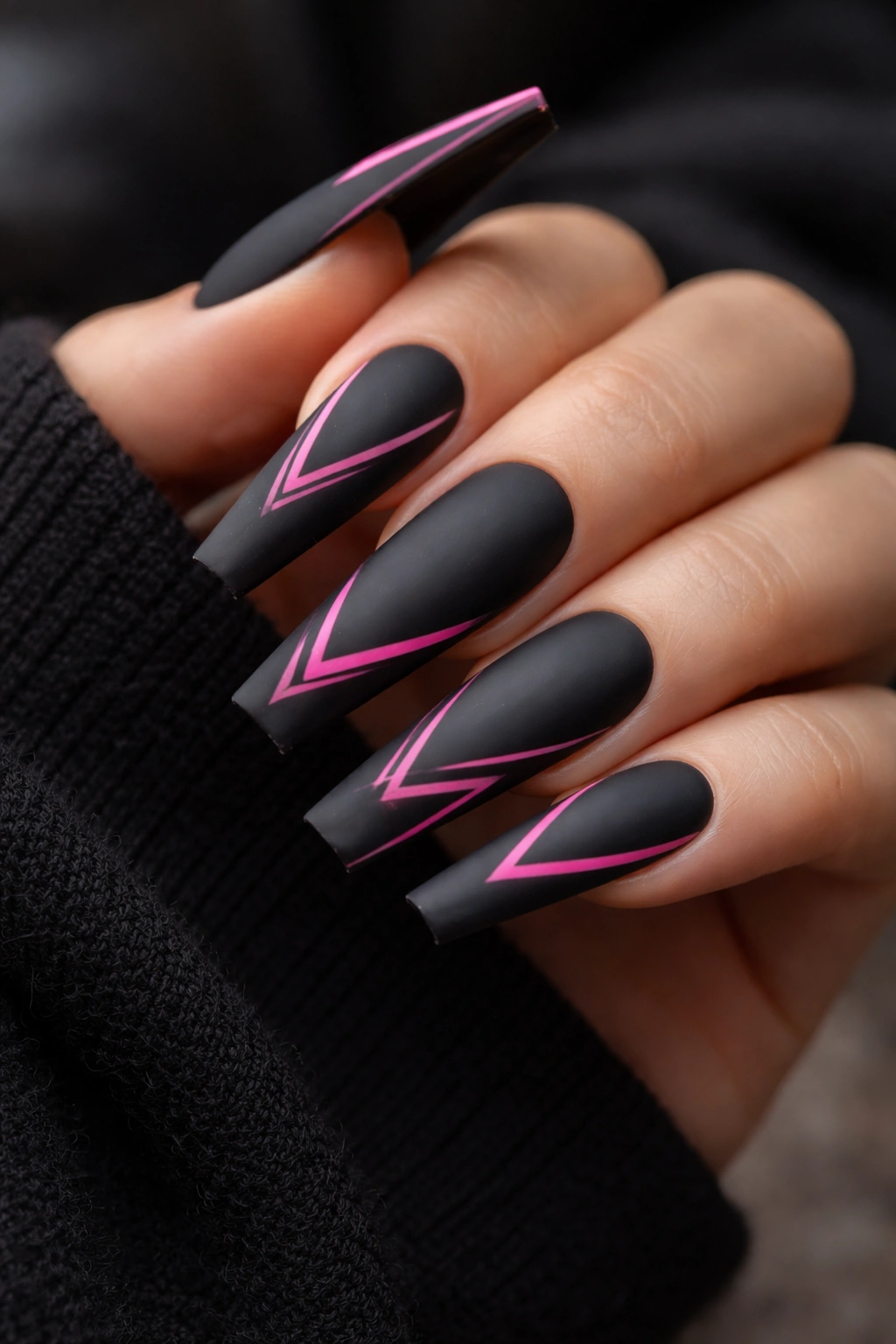 Close-up of coffin nails with matte charcoal base and neon pink accents