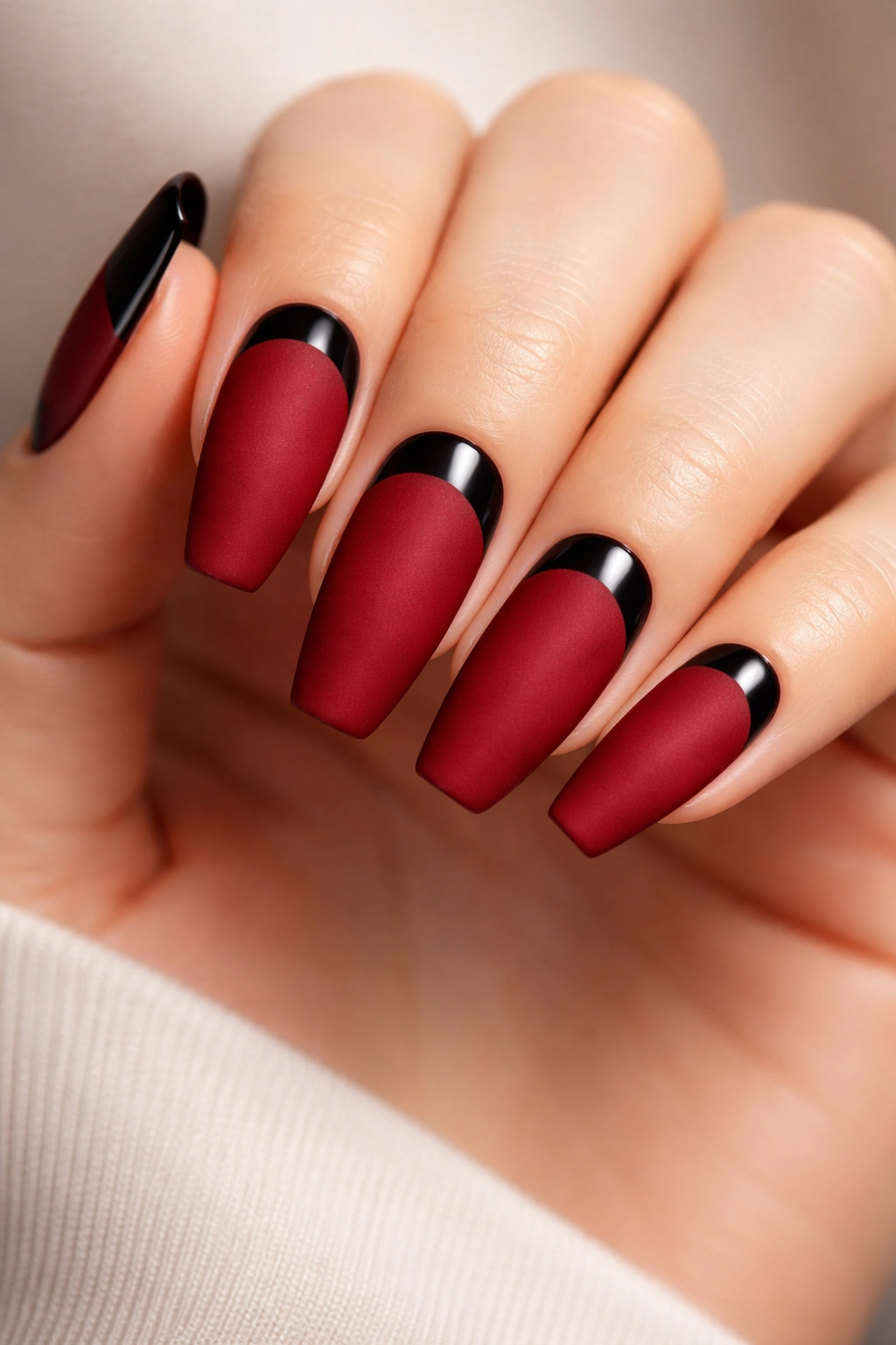 Matte crimson nails with glossy black half-moon near cuticle
