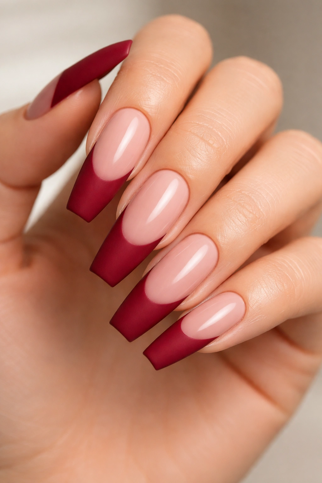 Matte crimson tips over glossy nude base on long ballerina nails