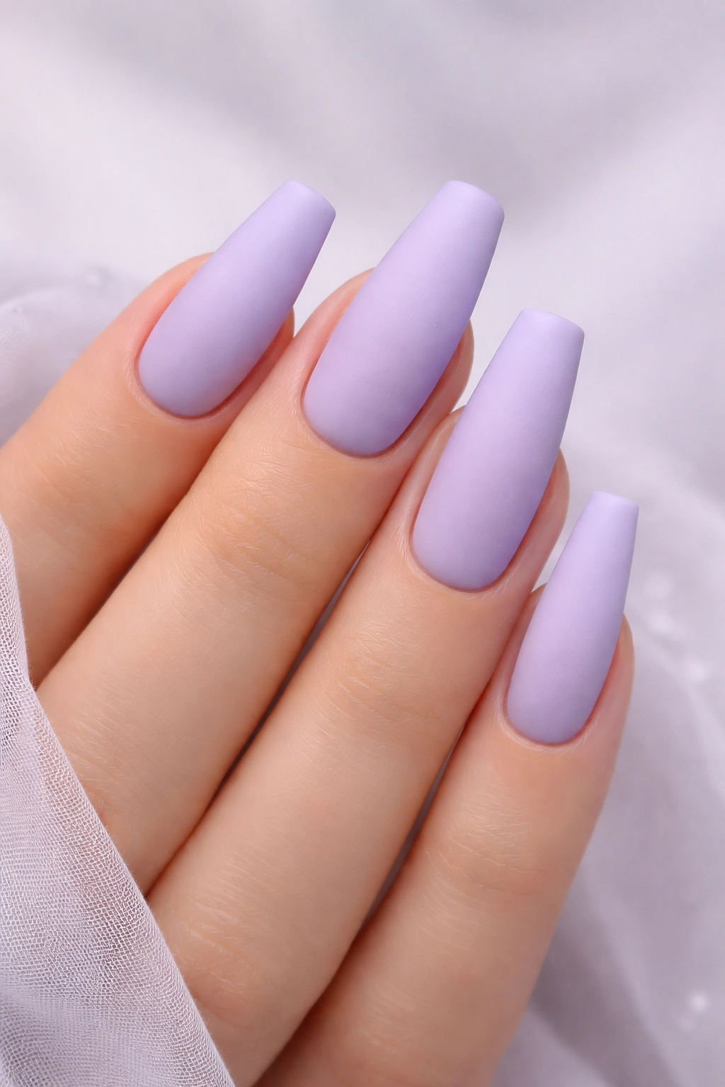 Close-up of matte lavender acrylic nails in soft lilac shade
