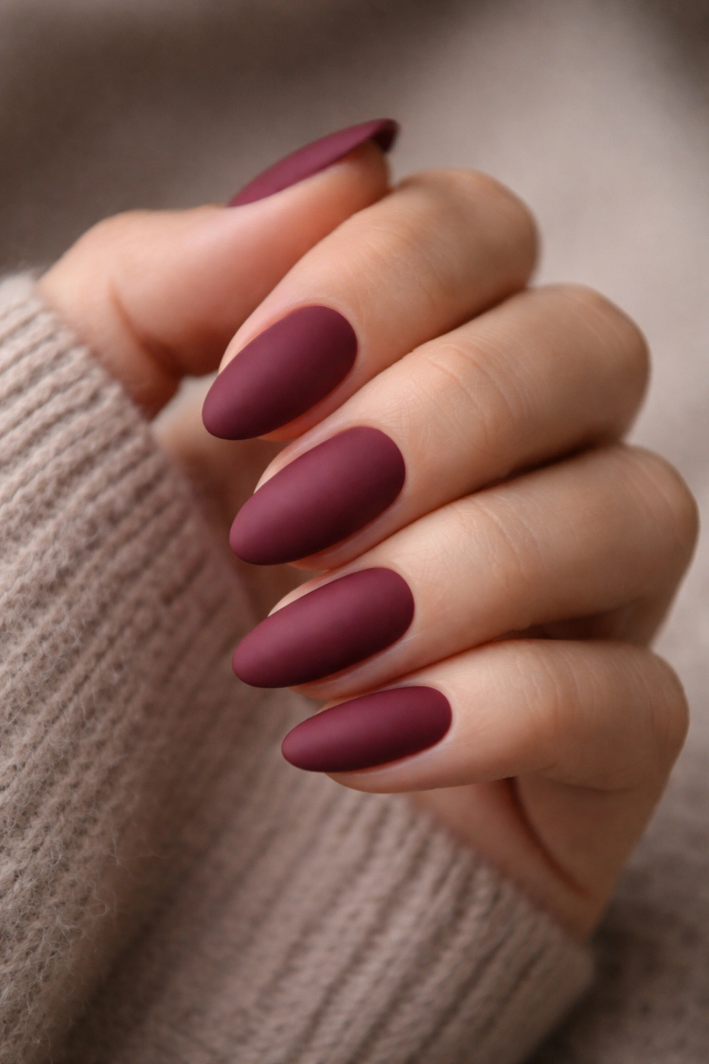 Close-up of matte maroon almond nails with velvety finish