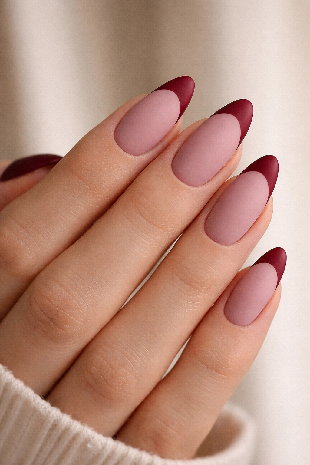 Close-up of almond nails with dusty pink matte base and wine red tips.