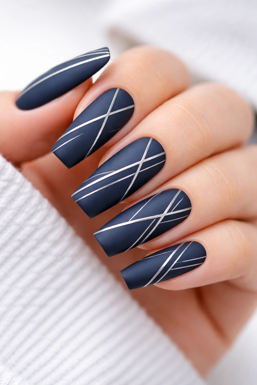 Matte navy nails with silver geometric lines close-up