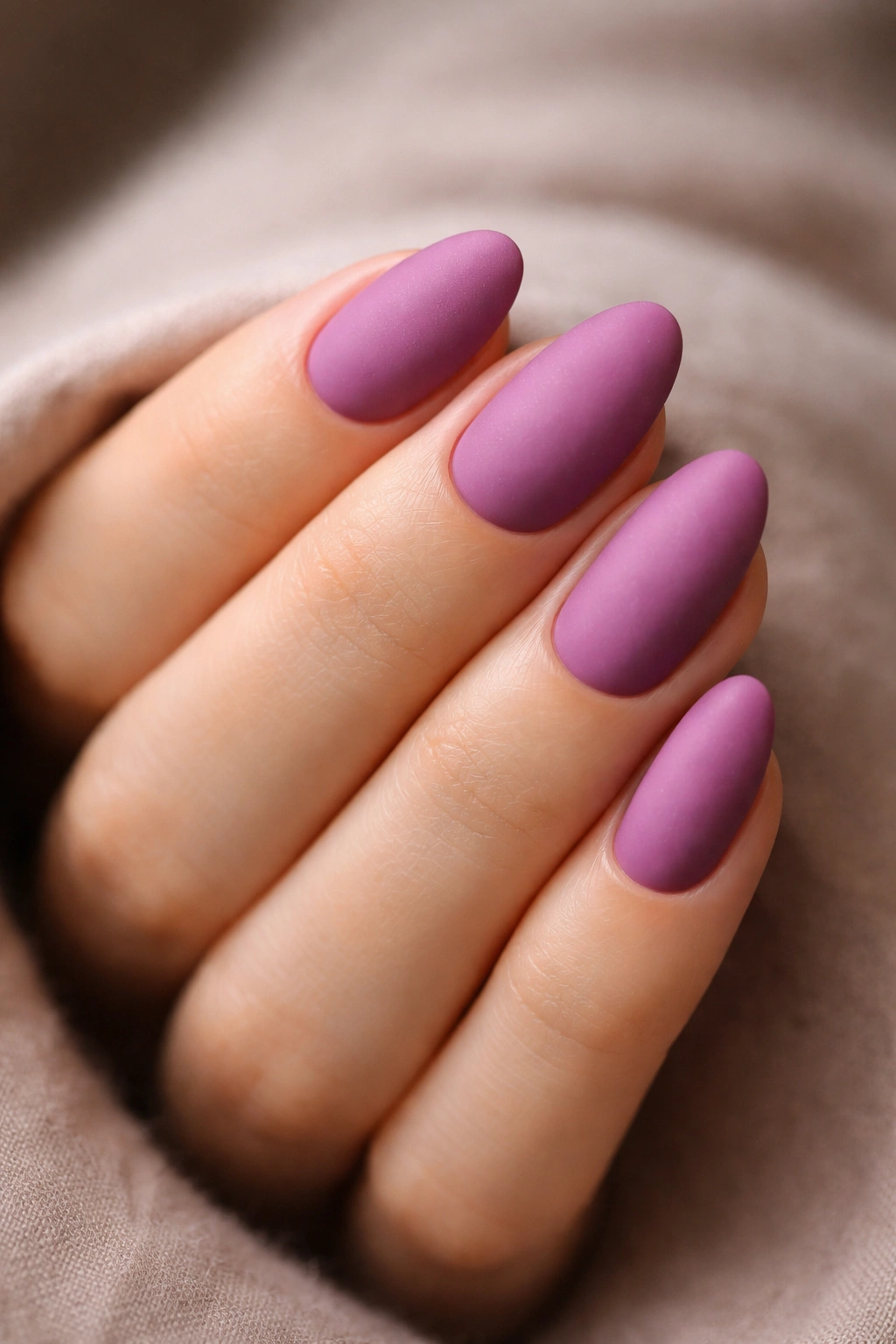 Close-up of short almond nails in matte orchid with velvet-like finish