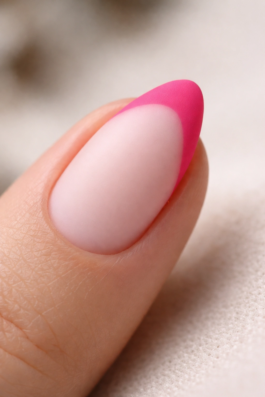 Close-up of a short almond nail with matte hot pink tip
