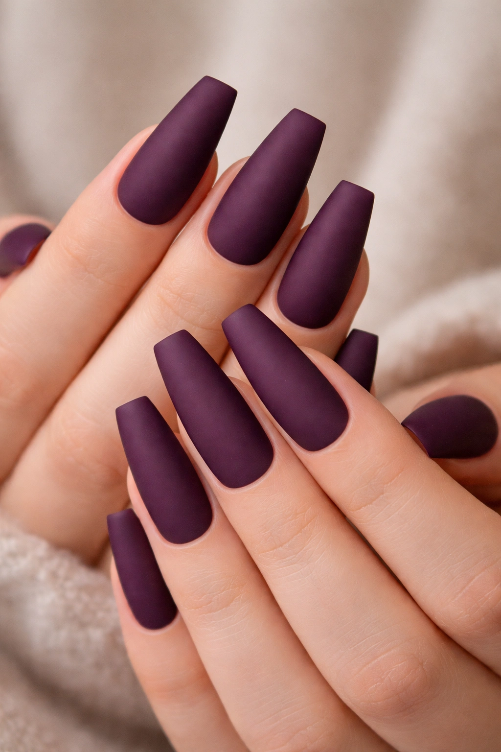 Matte plum coffin nails with velvet texture on a hand.