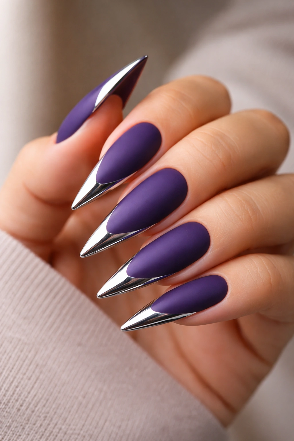 Close-up of matte purple stiletto nails with chrome tip accents