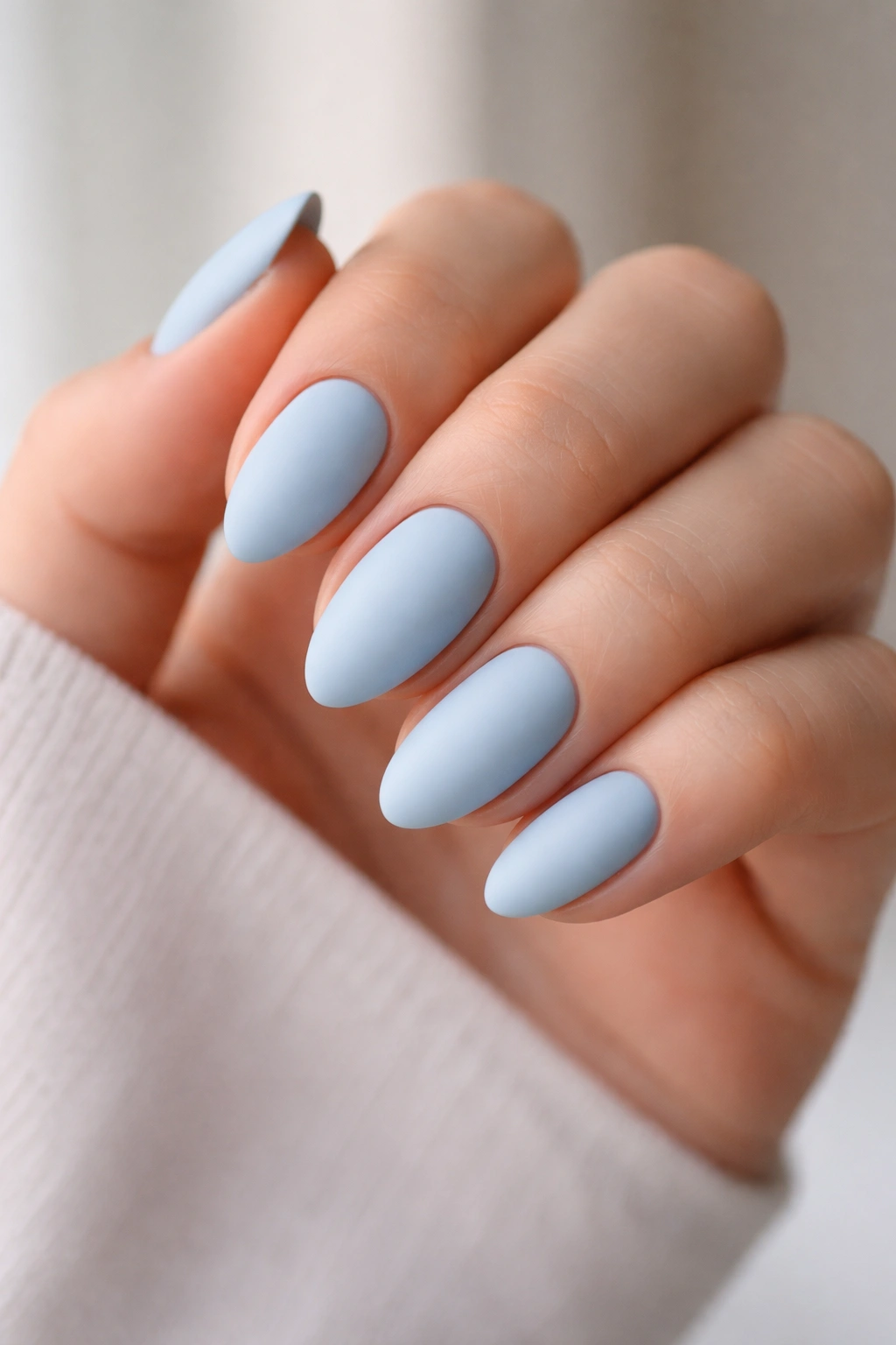 Close-up of matte sky blue short almond nails with velvety finish
