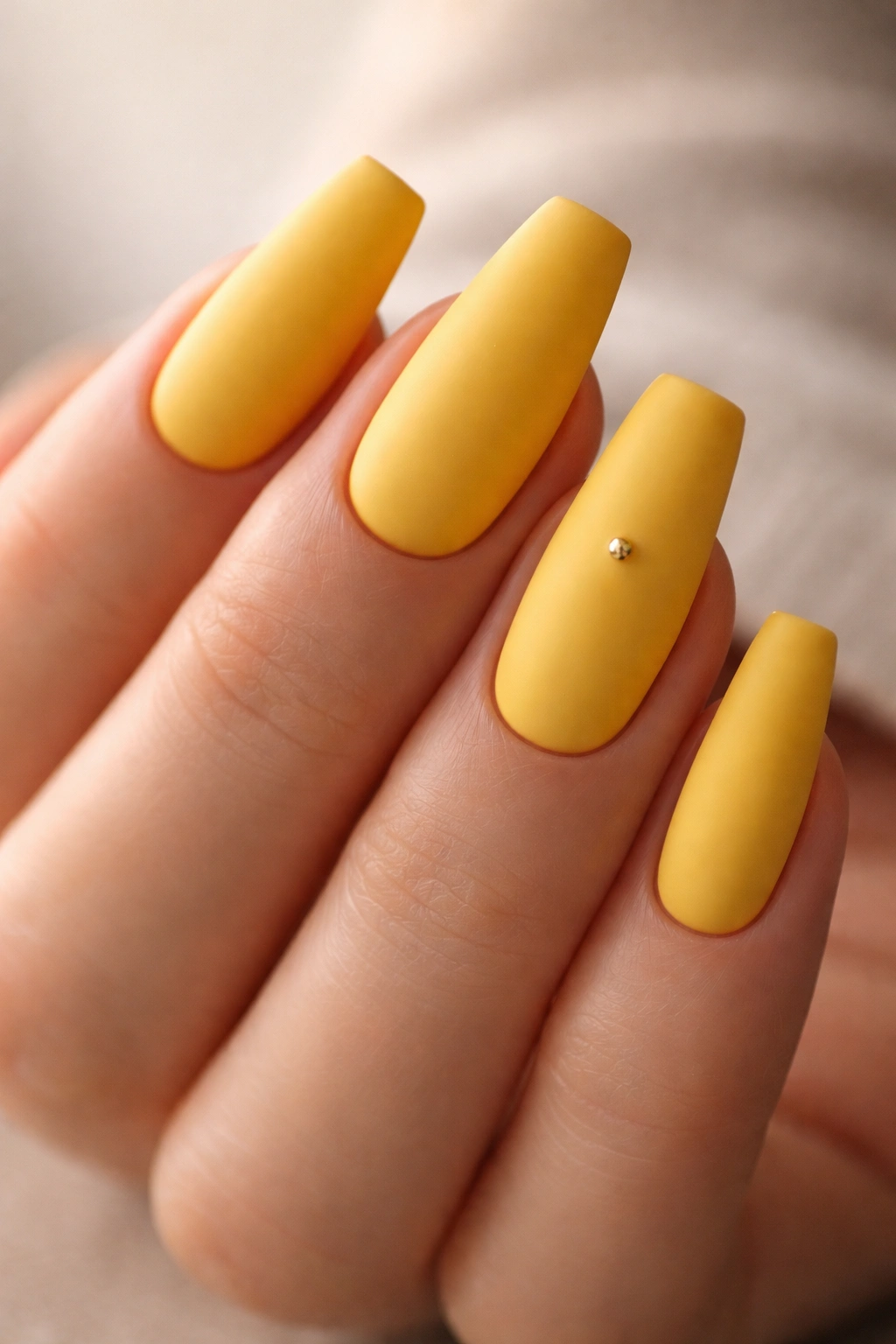 Matte sunflower yellow ballerina nails with a small stud accent